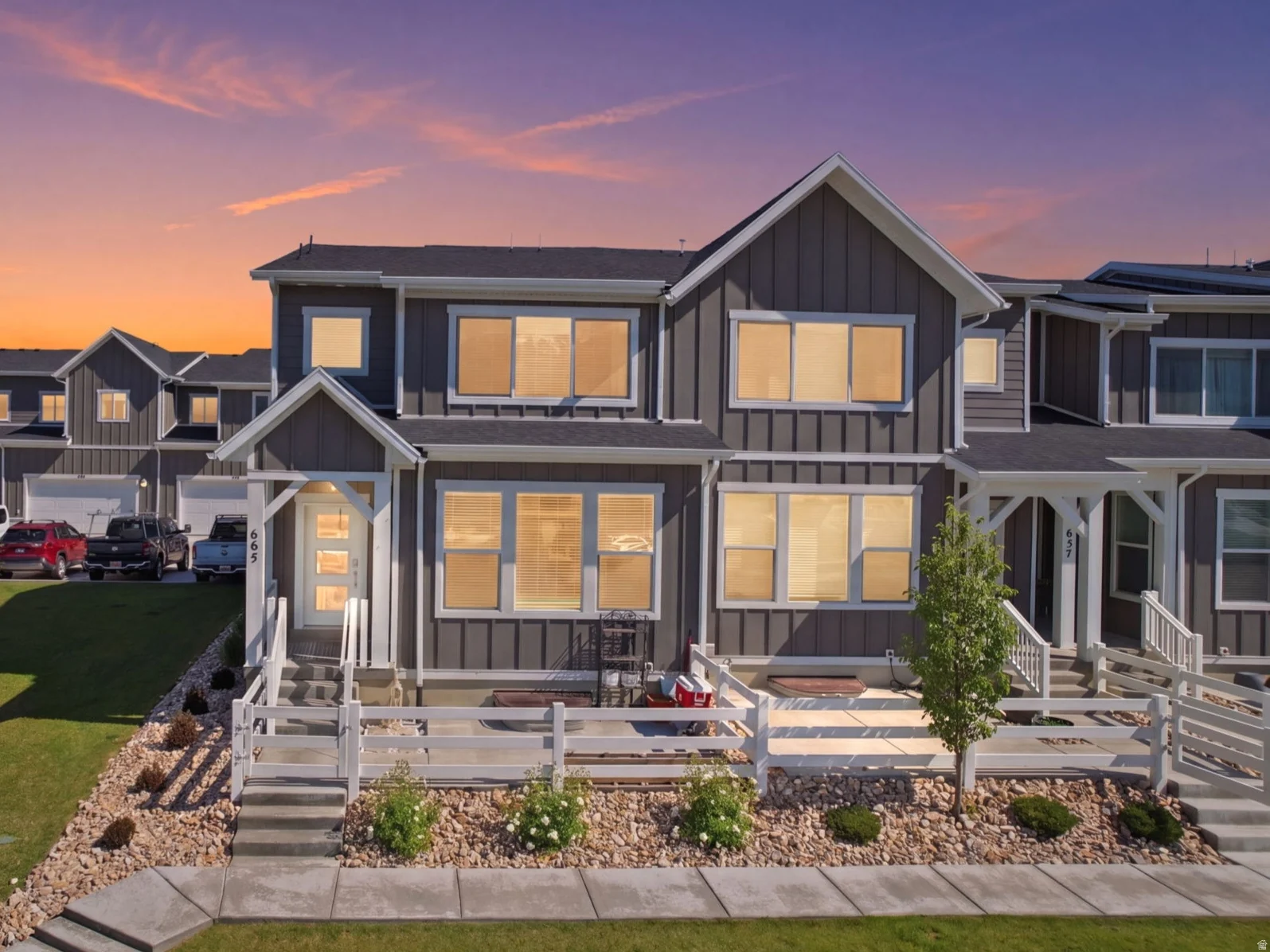 Modern gray facade with white trim, featuring multiple large windows and a front porch